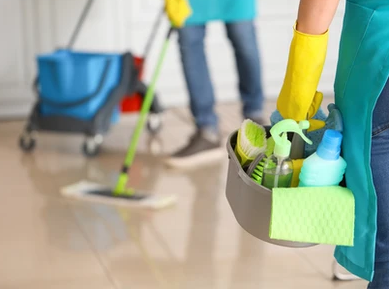 Blurred cleaning staff with focus on their cleaning equipment of bucket with cleaning products and a mop and bucket. 