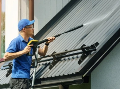 Man doing pressure washing on a roof